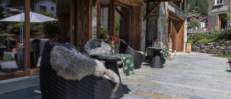 A cozy outdoor seating area with wicker furniture and a stone floor.