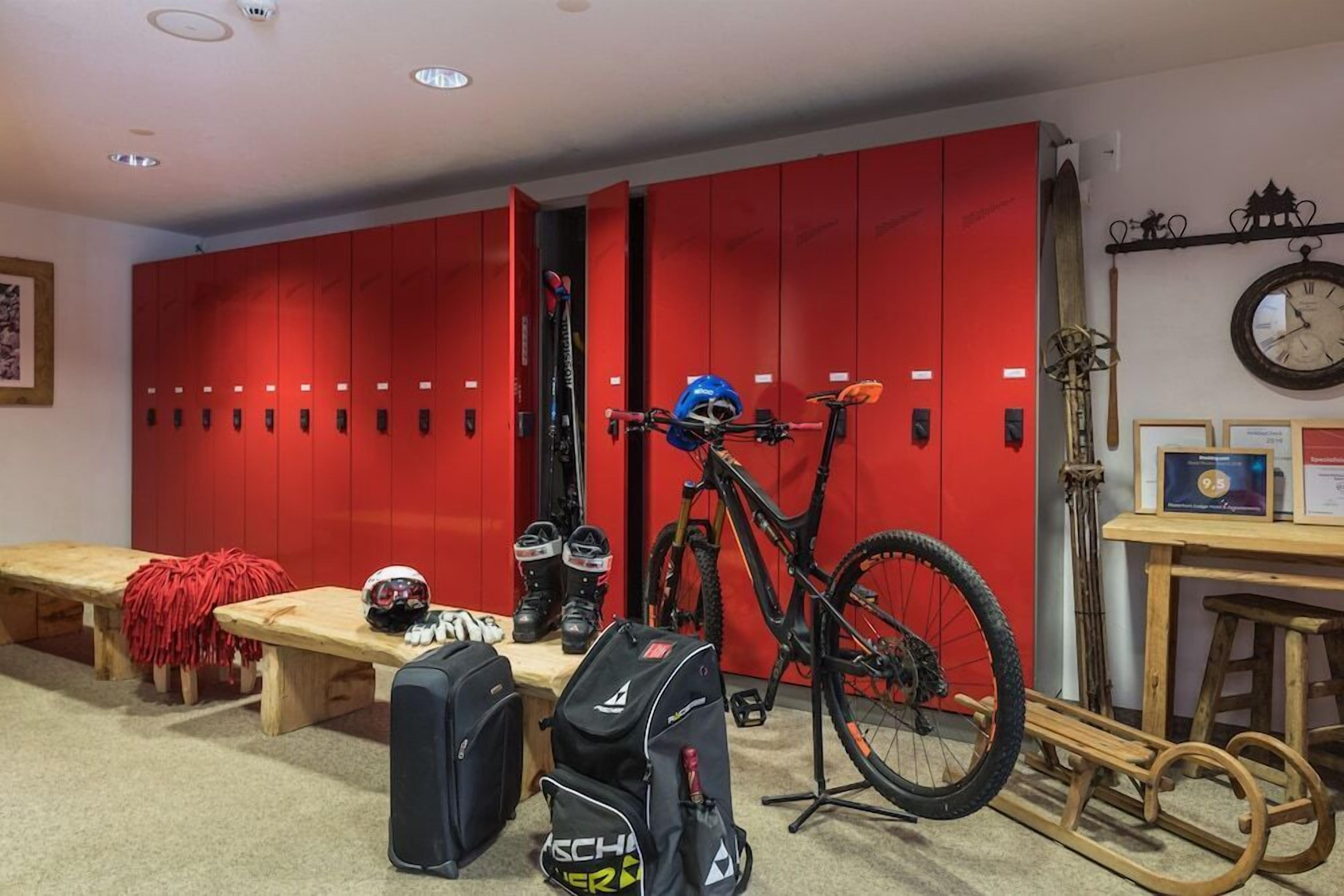 A room with red lockers, a bicycle, and a wooden bench.