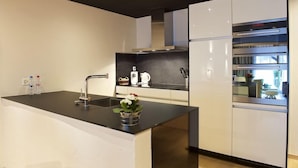 Een moderne keuken met een centraal eiland, roestvrijstalen apparatuur en een zwart aanrecht.