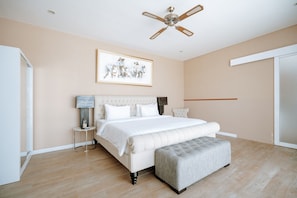 Ein Schlafzimmer mit einem Bett, einem Deckenventilator, einem gerahmten Bild und einem Nachttisch.