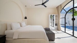 A modern bedroom with a large bed, a ceiling fan, and a view of a swimming pool. - The Grand Daha A Luxury Resort and Spa (Seminyak)