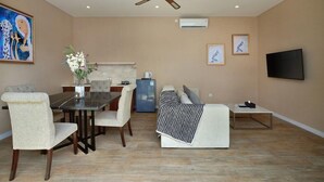 A living room with a dining table, chairs, a sofa, a TV, and a ceiling fan. - The Grand Daha A Luxury Resort and Spa (Seminyak)
