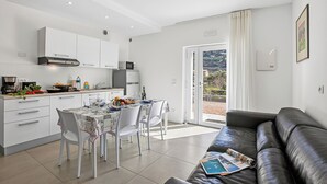 Una cocina moderna con armarios blancos, una mesa de comedor con sillas y un sofá de cuero.