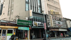 A multi-story building with a prominent 'WOW HOTEL' sign, a storefront with a green awning, and a street with pedestrians. - Palette Georgetown Formerly WoW Hotel (George Town)