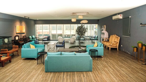 A spacious living area with teal sofas, wooden furniture, a large window, and a modern chandelier. - Palette Georgetown Formerly WoW Hotel (George Town)