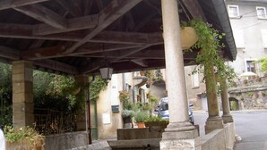 A covered outdoor area with stone columns, a wooden ceiling, and potted plants. - Le Cocon des Monts dOr (Saint-Germain-au-Mont-d'Or)