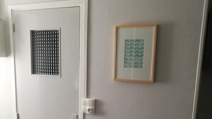 A hallway with a door, a wall-mounted light switch, and a framed picture. - Le Cocon des Monts dOr (Saint-Germain-au-Mont-d'Or)