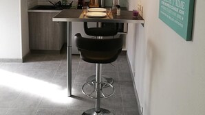 A modern kitchen with a dining area, including a bar stool and a pendant light. - Le Cocon des Monts dOr (Saint-Germain-au-Mont-d'Or)