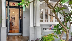 A building entrance with a glass door, a small porch area, and a tree with green leaves. - Manly Designer Studios (Sydney)