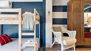 A room with a bunk bed, a wicker chair, and a wooden cabinet. - Manly Designer Studios (Sydney)