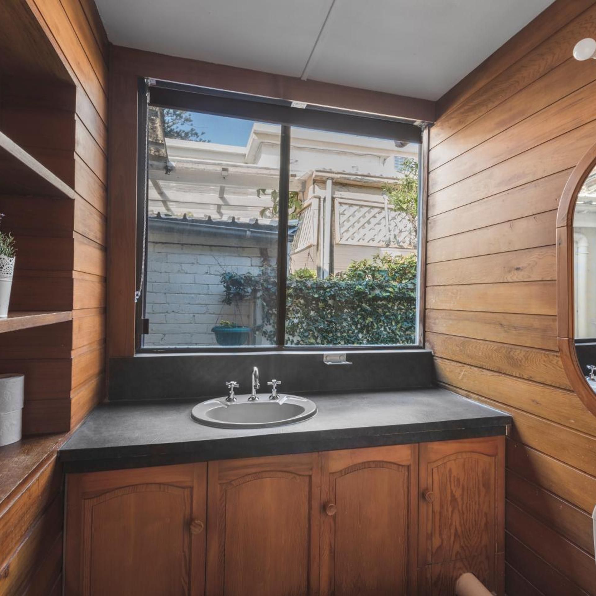 A wooden interior with a window, a sink, and cabinets.