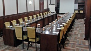 Une salle de conférence avec une longue table, des chaises et un tableau blanc.