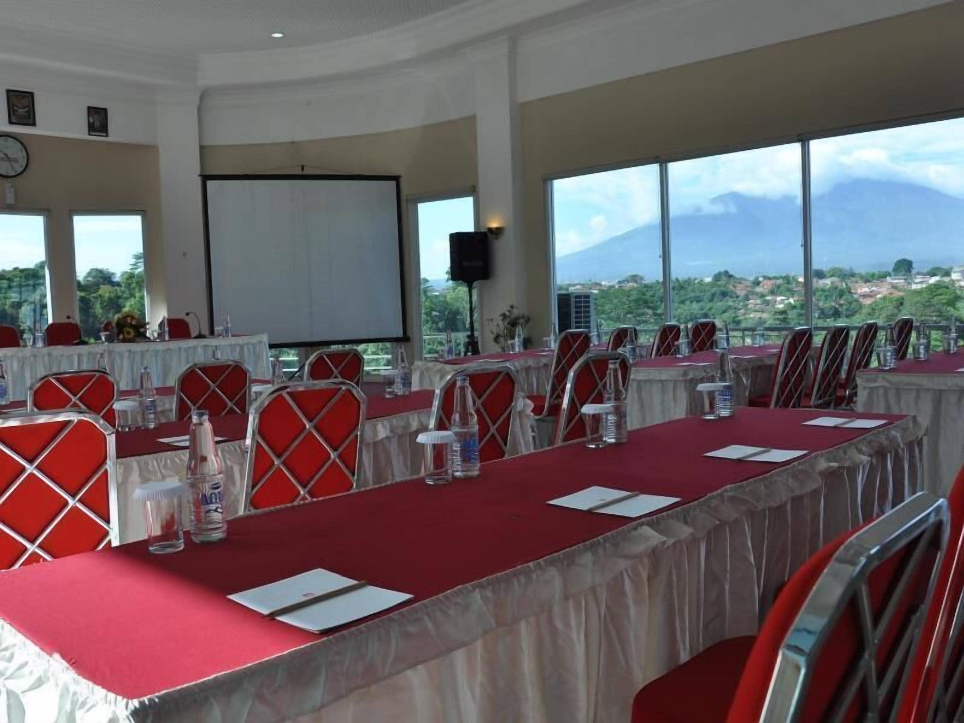 A conference room with multiple tables, chairs, and a large screen.