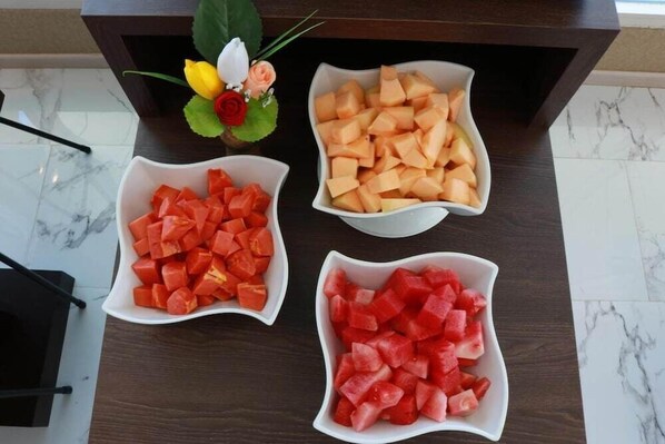 Tres tazones blancos con trozos de sandía y melón sobre una mesa de madera oscura.