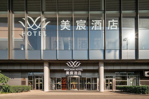A modern hotel building with large glass windows and a prominent hotel sign.