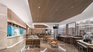 En modern hotellobby med marmorgolv, trädetaljer och en central sittgrupp.