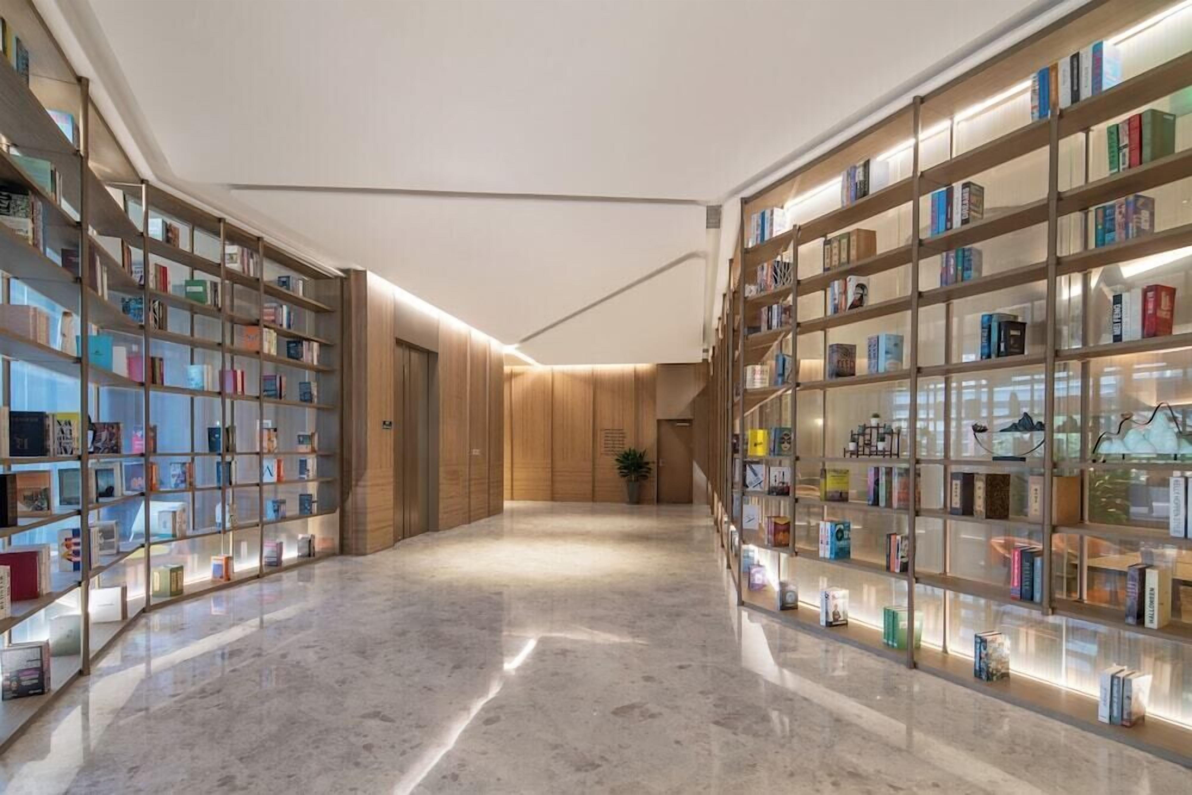 Um corredor amplo com piso de mármore e estantes de livros em ambos os lados.