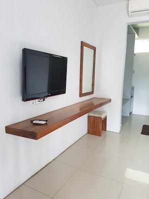 Ein modernes Wohnzimmer mit einem flachbildfernseher an einer weißen Wand, einer Holzbank und einem Fernseherlebnis.