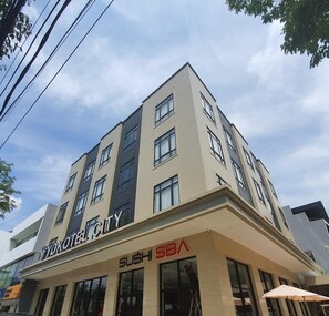Um edifício de vários andares com um letreiro 'SUSHI SBB' no andar térreo, indicando um restaurante de sushi.