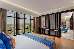 Una habitación de hotel moderna con una cama grande, vistas a la ciudad y un balcón con una silla.