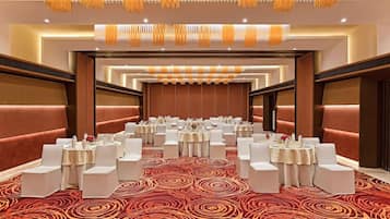 A conference room with round tables, white chairs, and a patterned carpet.