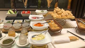 A buffet table with various food items and condiments.