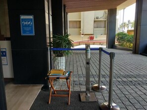 Entrada d'hotel amb una barrera blava, una taquilla d'hostes i una planta en test.