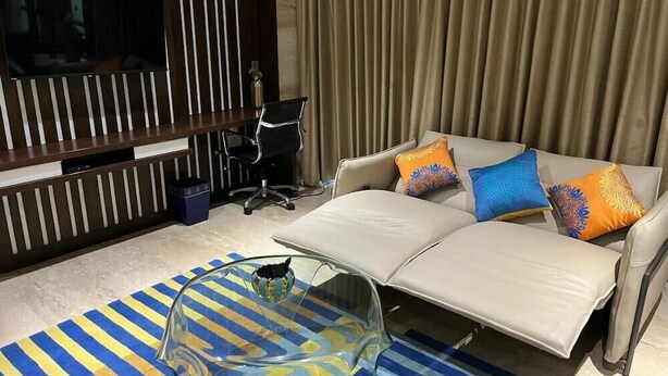 A modern living room with a sofa, a TV, a coffee table, and a striped rug.