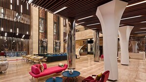 A spacious lobby with a red sofa, red armchairs, and a pool table.