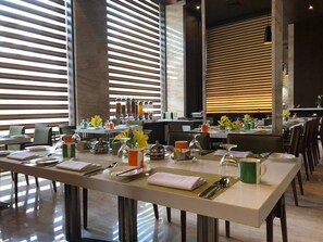 A modern dining area with long tables set for breakfast, featuring a variety of breakfast items and utensils. - Fortune Park Vellore (Katpadi)