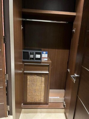 Un armario de madera con microondas integrado y una pequeña cesta.