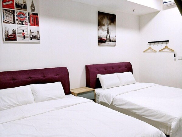 A hotel room with two beds, white bedding, and a red headboard. There is a poster of the Eiffel Tower on the wall and a coat rack with hangers. - Tropicana 218 Macalister (George Town)