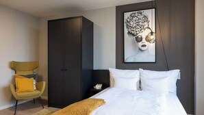Une chambre à coucher comprenant un lit, une armoire, une chaise et une œuvre d’art accrochée au mur.