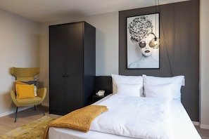 A bedroom with a bed, a wardrobe, a chair, and a wall-mounted artwork. - Joyn Cologne (Cologne)