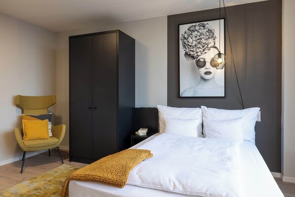 A bedroom with a bed, a wardrobe, a chair, and a wall-mounted artwork. - Joyn Cologne (Cologne)
