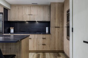 A modern kitchen with wooden cabinets, a black countertop, and a built-in oven.