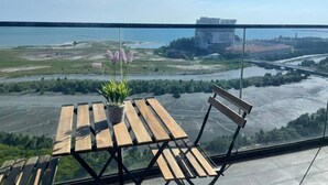 Un balcón con mesa y sillas de madera, una planta en maceta y vistas de un río y edificios.
