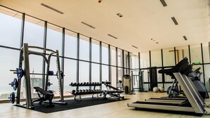 Un gimnasio con equipamiento de levantamiento de pesas, cintas de correr y una banca.