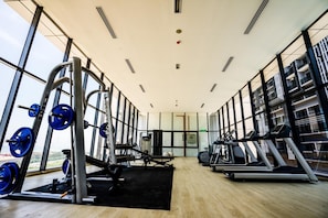 A gym with weightlifting equipment, treadmills, and a view of the city. - Imperio Residences by Lets Stay (Malacca City)