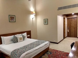 Een hotelkamer met een bed, een bureau en een deur.