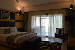 Une chambre d’hôtel avec un lit, une chaise, un bureau et une fenêtre avec des rideaux.