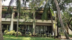 A multi-story hotel with balconies, surrounded by palm trees and greenery. - Welcomhotel by ITC Hotels, Kences Palm Beach (Tirukalukundram)