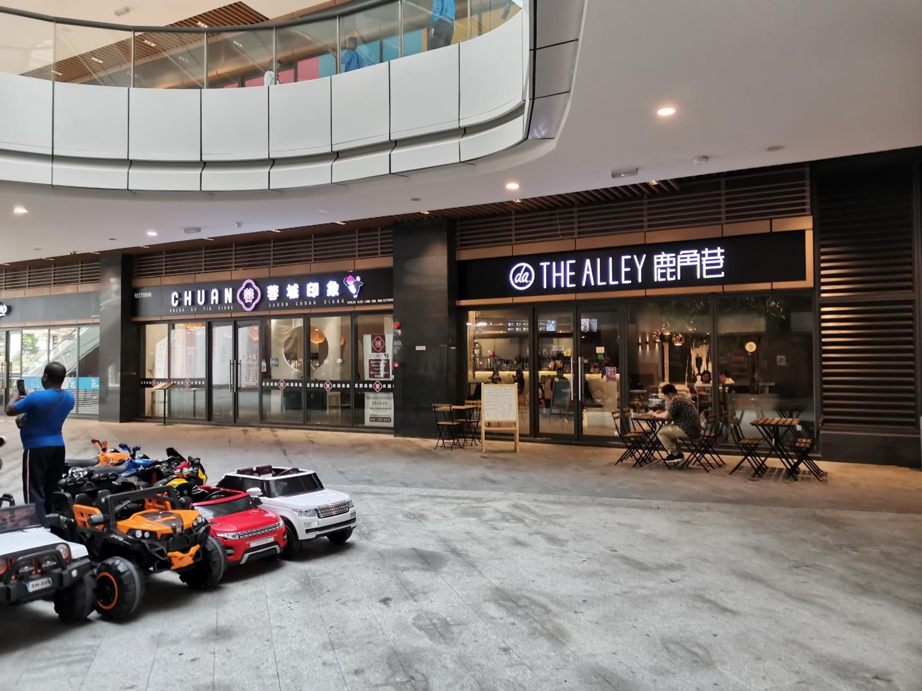A modern shopping mall interior with a food court area.