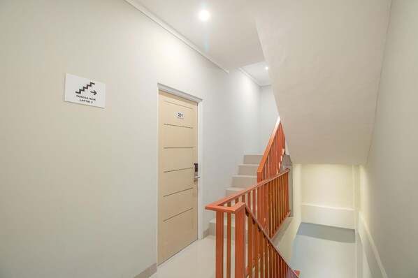 A staircase with a wooden handrail and a sign indicating the direction to the third floor. - Denz Express Pondok Labu (Jakarta)