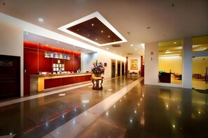 A hotel lobby with a reception desk, a flower arrangement, and a modern ceiling design. - Kingwood Hotel Mukah (Borneo (MY))