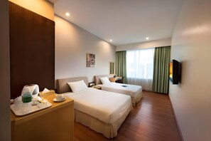 A hotel room with two beds, a desk with a tray of breakfast items, a flat-screen TV, and a large window with curtains. - Kingwood Hotel Mukah (Borneo (MY))