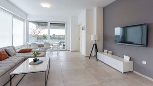 A modern living room with a sofa, coffee table, and a TV mounted on the wall. - Apartment Sang Near The Beach, Pula, Croatia (Pula)