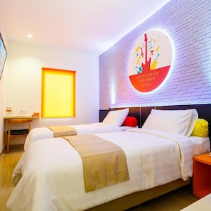 A hotel room with two beds, a desk, and a wall with a circular design. - Front One Inn Muntilan (Muntilan)
