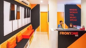 Een receptiegedeelte van een hotel, modern ingericht, met een receptiebalie, zithoek en een muur met een inspirerende quote.