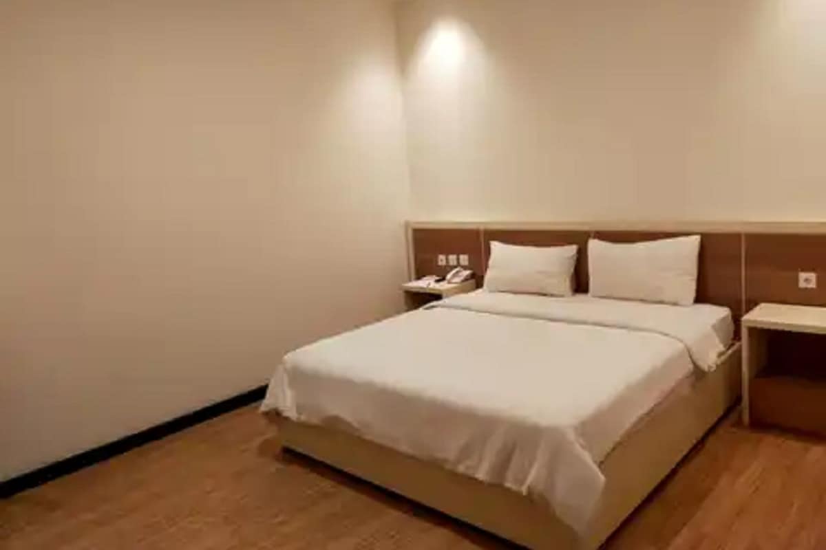 A hotel room with a bed, bedside tables, and a wall-mounted phone.